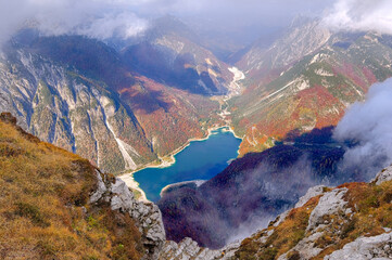 landscape of golden orange and red colors of autumn alps slovenia italy low clouds and first snow bright sunny day