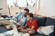 © gstockstudio - Happy father helping his son with homework while homeschooling in the living room