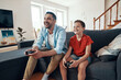 © gstockstudio - Happy young father and son playing video games while spending time at home