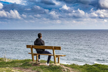 Rear View Of Man On Bench Facing Sea