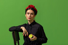 Close-up Young Beautiful Woman In Image Of Famous Painter, Artist Frida Kahlo On Green Background. Retro Style, Comparison Of Eras Concept.