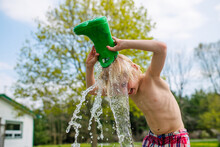Canada, Kingston, Shirtless Boy Pouring Water From Rubber Boot On Head
