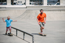 USA, California, Ventura, Father And Son Skateboarding In Skate Park