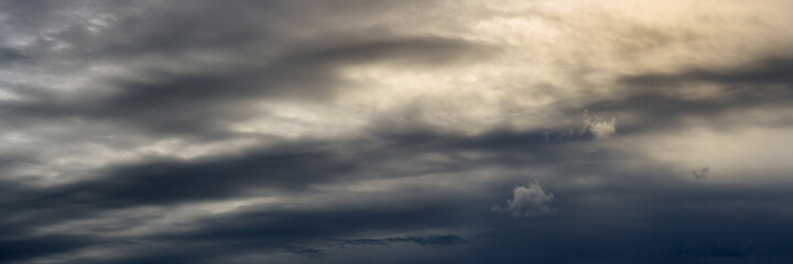 Wall Mural - wide panoramic view of dramatic cloudy sky with back sunlight