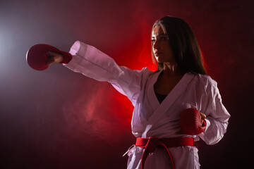 Wall Mural - girl exercising karate punch against red fog background.