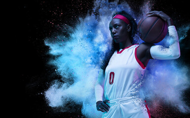 Wall Mural - One young woman sportsman basketball player in explosion of colored neon powder isolated on dark background