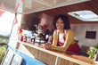 © Wavebreak Media - Portrait of smiling mixed race woman leaning on counter in food truck