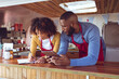 © Wavebreak Media - Smiling diverse couple behind counter using tablet and writing in food truck