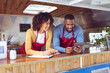 © Wavebreak Media - Smiling diverse couple behind counter using tablet in food truck