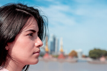 Close-up of a girl's face looking in profile, she is outdoors in an urban, industrial setting.