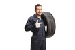 Auto mechanic holding a of car tire and pointing