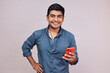 © alex fernandezch - Hombre joven y feliz con un celular. Modelo aislado en fondo blanco con camisa azul