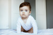 © KatrinaEra - Portrait of toddler boy baby in white bodysuit on the bed in bedroom. Happy childhood concept