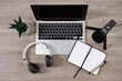 podcast and blogging concept - top view of workplace with laptop, microphone, headphones, open notepad and pen over wooden table background