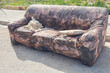 Old damaged and broken sofa abandoned on the street.