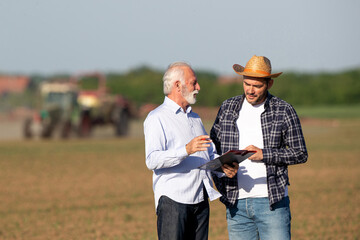 Canvas Print - Farmer and insurance sales representative talking in field