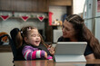 © Vergani Fotografia - baby with disability and mother laughing and watching video online in tablet..