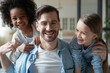 © fizkes - Close up portrait of overjoyed young Caucasian father have fun play with excited small multiracial daughters at home. Happy dad feel playful with diverse multiethnic girls children. Adoption concept.