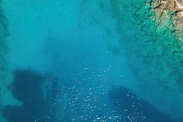 Aerial view of turquoise and clear sea water surface at sunny day. Summer holiday and travel to sea