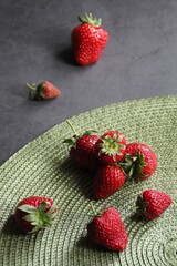 Wall Mural - fresh strawberries, strawberries on a green pad, dark background, spring red fruits, strawberries with stalks