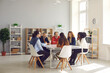© Studio Romantic - Team of mixed race business people sitting around big table in modern office space. Group of diverse company employees discussing projects and taking decisions together in corporate meeting