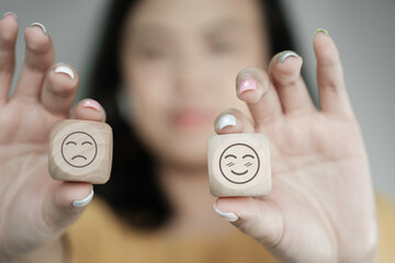 Wall Mural - Woman hand holding smile and angry face on wooden cube, positive or negative thinking, mental health, Business satisfaction assessment , world mental health day concept	