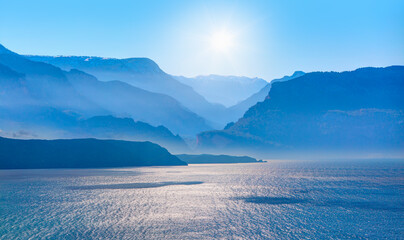 Amazing blue mountains over the blue seav with gorgeous blue sky in the background