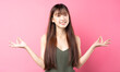 Portrait of a beautiful young asian girl posing on a pink background