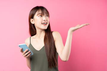 Wall Mural - Beautiful young asian girl using phone on pink background