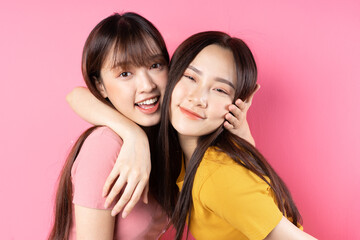 Wall Mural - Portrait of two beautiful young Asian girls posing on pink background