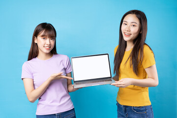 Wall Mural - Two beautiful young asian girls using laptop on blue background