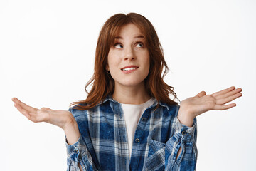 Wall Mural - I dont know. Confused redhead girl shrugging and looking up with indecisive, unsure face, cant make decision, have no clue, standing puzzled against white background