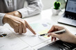 © kamiphotos - Two business partners are brainstorming on planning, managing and solving company problems, they are pointing at the company financial documents. The concept of business management for growth.