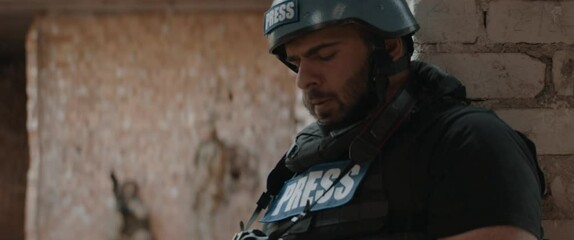 Sticker - Hispanic male war journalist wearing protective helmet and bulletproof vest gear taking photos during military operation. Shot with 2x anamorphic lens