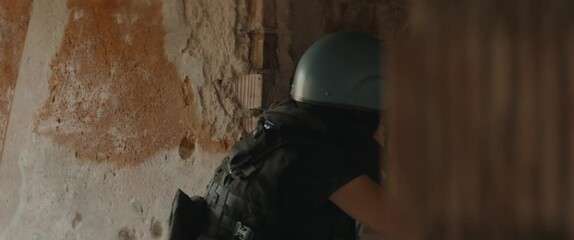 Wall Mural - Caucasian female war journalist wearing protective helmet and bulletproof vest gear taking photos during military operation. Shot with 2x anamorphic lens