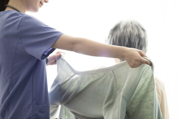 Wall Mural - Nurse helping patient put on clothes