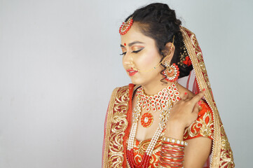 Beautiful Indian woman in a traditional red sari dress posing against a white wall