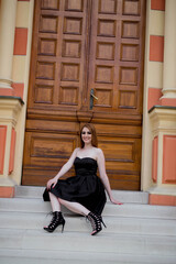 Wall Mural - Vertical shot of a white Caucasian woman wearing a black classic dress and posing for a picture