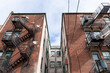 Centered view of a light well between apartment building wings, metal fire escapes, urban housing composition, horizontal aspect