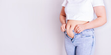 A Woman Dresses In Jeans After Giving Birth. The Concept Of The Diet-close-up Of Women's Hands Can Not Button Their Pants Because Of The Increase In Fat On The Thighs After Childbirth
