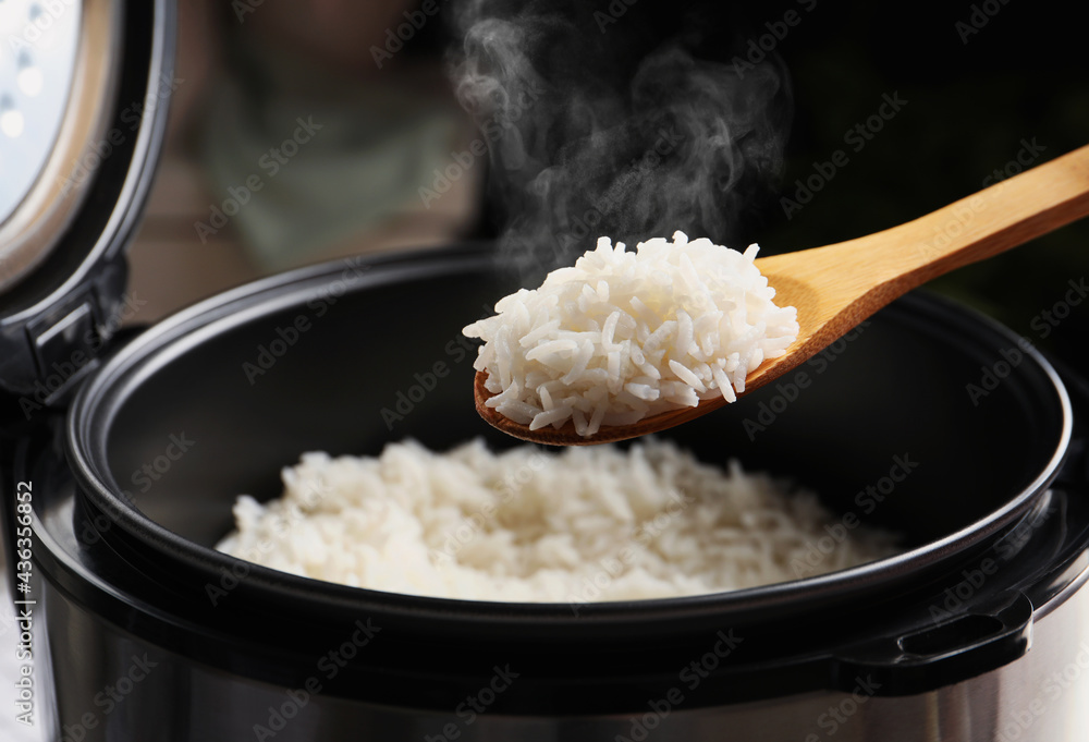 Very Hot Rice Spoon with tasty hot rice over cooker, closeup Stock Photo | Adobe Stock
