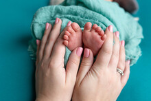 Baby Feet In The Hands Of The Mother. Parents Rings On The Toes Of A Newborn