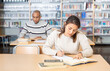 © JackF - Young adult woman working with books, finding information at library