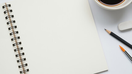 Wall Mural - open blank notebook with cup of coffee, paintbrush, pencil and eraser on white background, copy spac