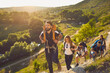 Group of young boys and girls hikers with backpacks on their shoulders walking on the rocks in the countryside in summer weather. Concept of active recreation.