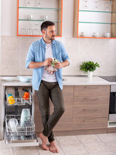 Attractive Young Man Wiping Cup Standing In Kitchen Barefoot.