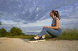 © Ahmed - Young woman looking at view while sitting in grassy field