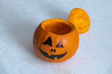 Wall Mural - Close-up view of Halloween pumpkin with drawn Jack O' Lantern face and without the top. Orange pumpkin stands on white table. Selective focus. Side view. Homemade Halloween decoration theme.