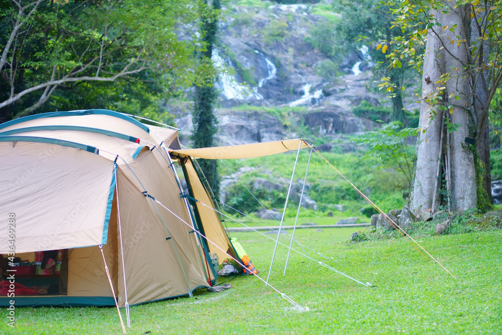 camping tent on nature waterfall with tree in green garden or forest by family camper for holiday relax and vacation travel trip to trekking picnic on meadow grass at khlong nam lai waterfall campsite - obrazy, fototapety, plakaty 