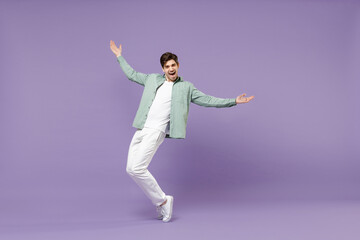 Poster - Full lengthoverjoyed caucasian man in casual mint shirt white t-shirt standing on toes dancing leaning back fooling around isolated on purple color background studio portrait People lifestyle concept.